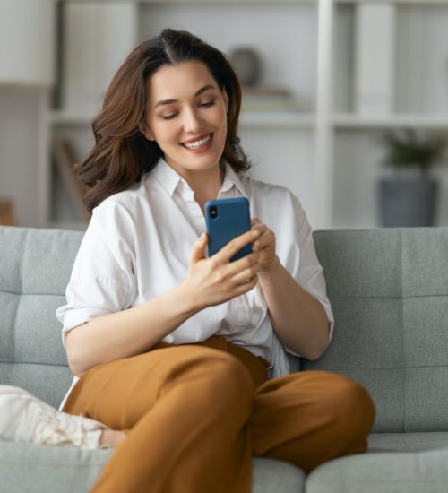 woman-is-using-a-phone-sitting-on-a-sofa.jpg